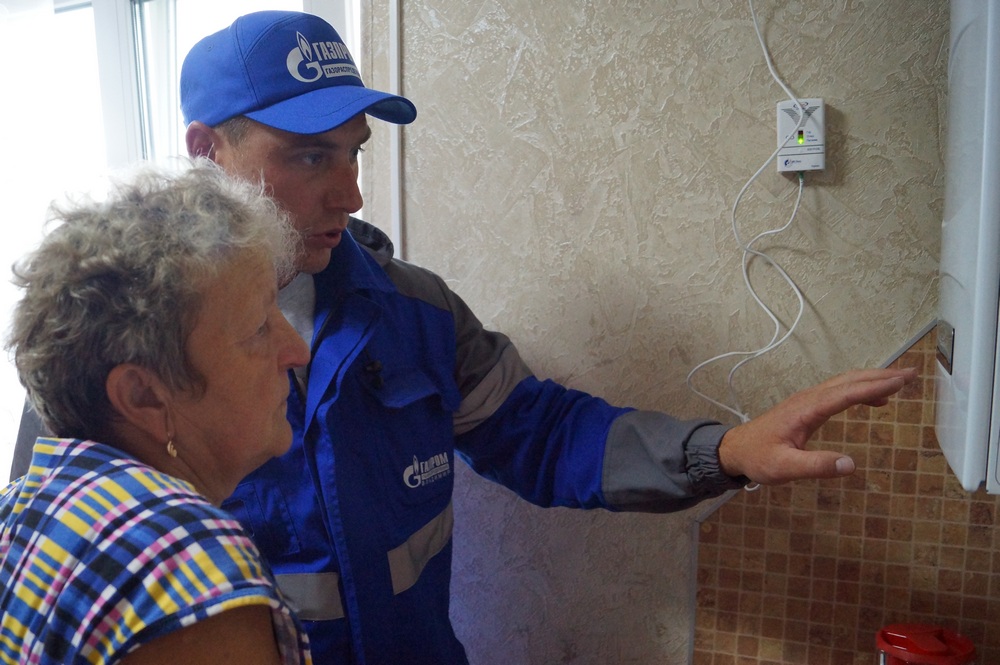 Работник газораспределительной компании объясняет хозяйке, как пользоваться газовым котлом Работник газораспределительной компании объясняет хозяйке, как пользоваться газовым котлом